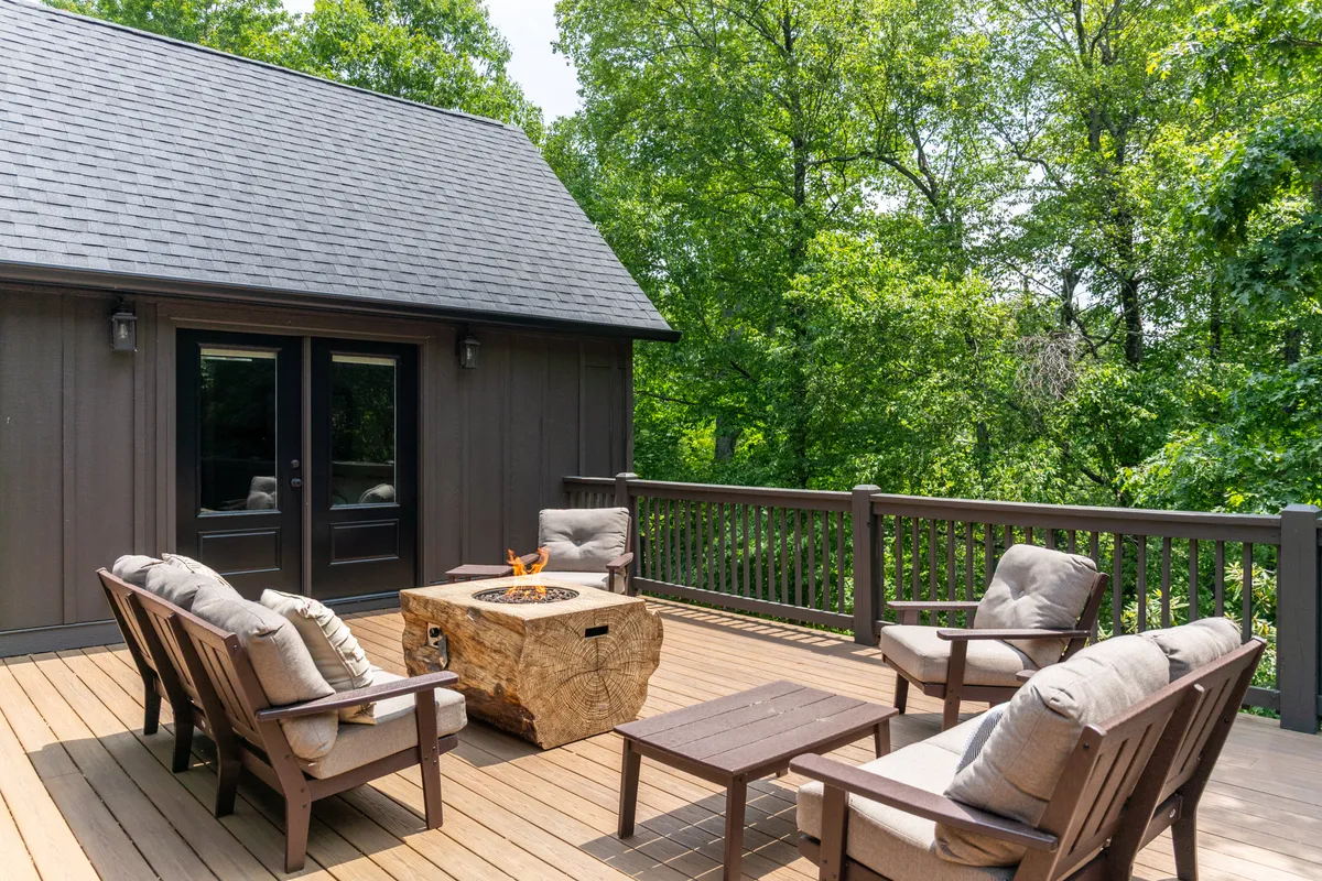 A cozy outdoor deck with a gas firetable, surrounded by comfortable seating and nestled among trees. The setting is perfect for enjoying mountain air, stargazing, or gathering with friends and family under the evening sky.