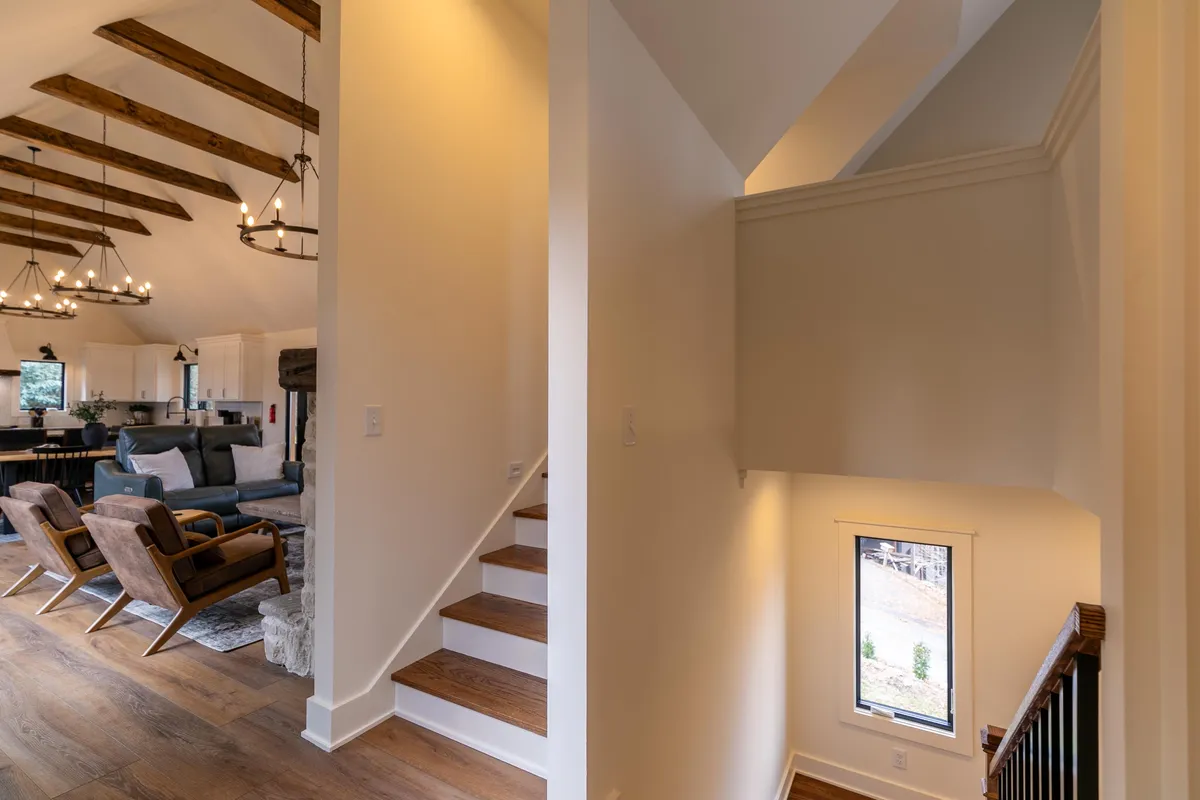 An inviting seating area with exposed wooden beams and a staircase leading to upper levels, ideal for gathering with friends or family. The space is open and encourages group interaction, echoing the communal, welcoming spirit of the retreat.