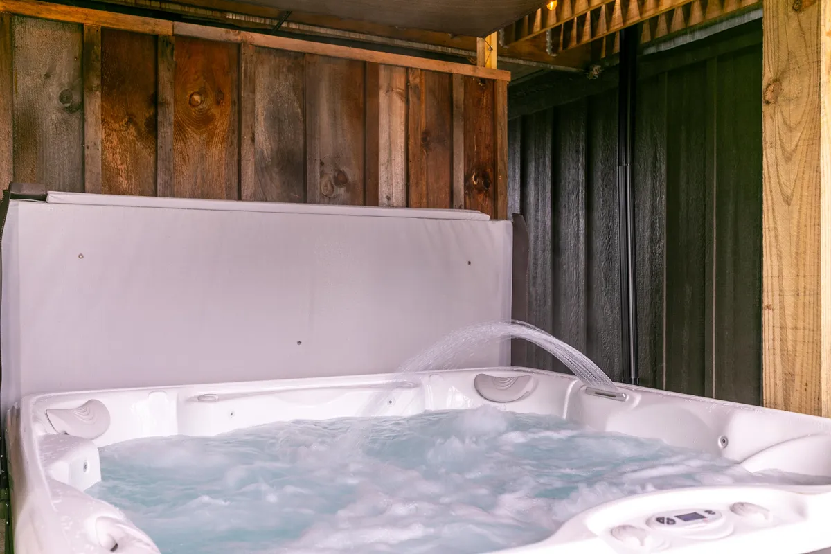 A tranquil hot tub surrounded by wooden paneling, with water jets creating a soothing environment. The setup hints at the potential for stargazing and unwinding, echoing the retreat’s promise of relaxation after a day spent outdoors.