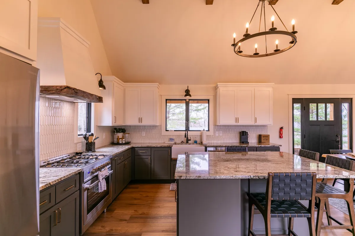 A close-up view of the chef’s kitchen, highlighting the expansive granite countertop, eat-in island with seating, a sleek gas stove, and a window view. The setup invites both cooking and conversation.