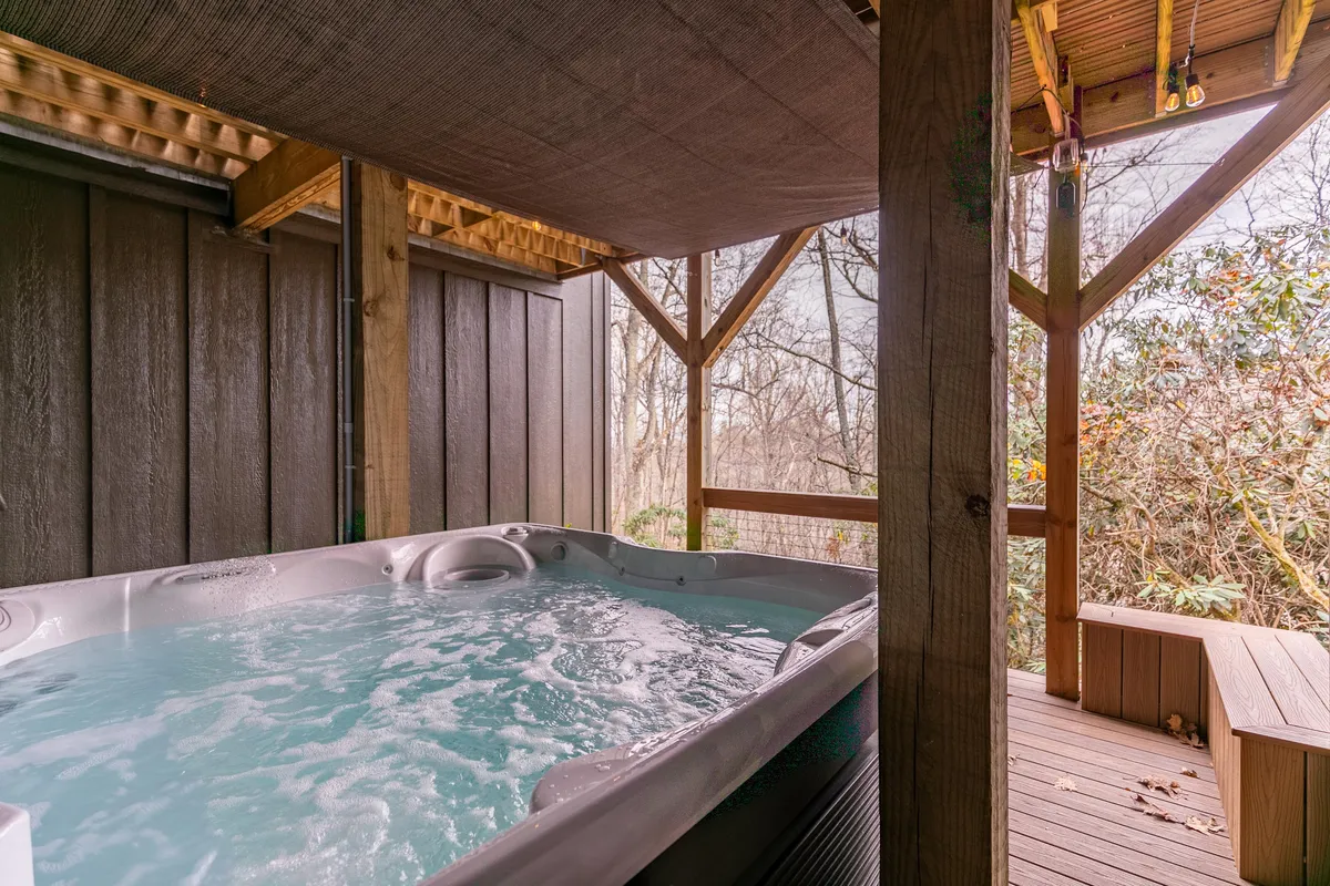 An inviting outdoor hot tub sits on a wooden deck, surrounded by lush greenery. The setting is peaceful, perfect for unwinding after a day of adventure.