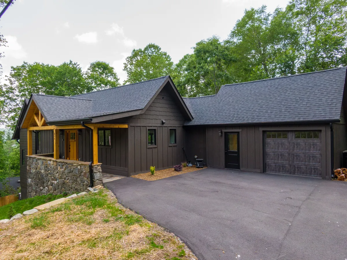The home's welcoming exterior includes a wooden entrance with stone accents, dark siding, and thoughtfully landscaped surroundings. The setting conveys a cozy, peaceful neighborhood perfect for strolls and family gatherings.
